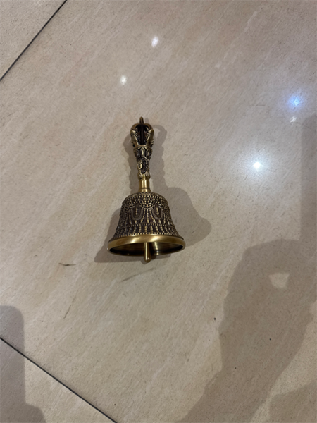 Chuông có cán cầm đặt trên nền gạch.
