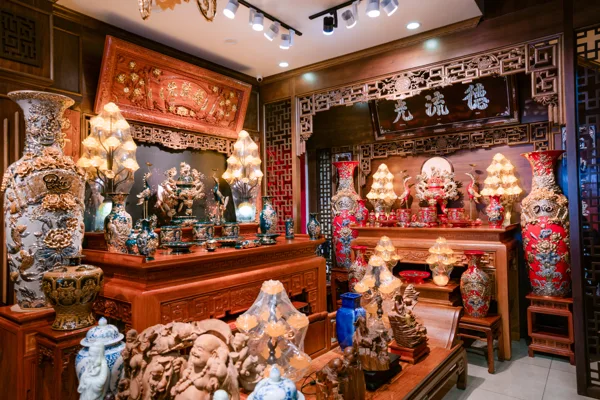 Hai tổ hợp đồ thờ xanh đậm và đỏ với chi tiết nổi, bình cao hai bên, đèn dạng hoa và hoành phi trên nền tường sẫm.