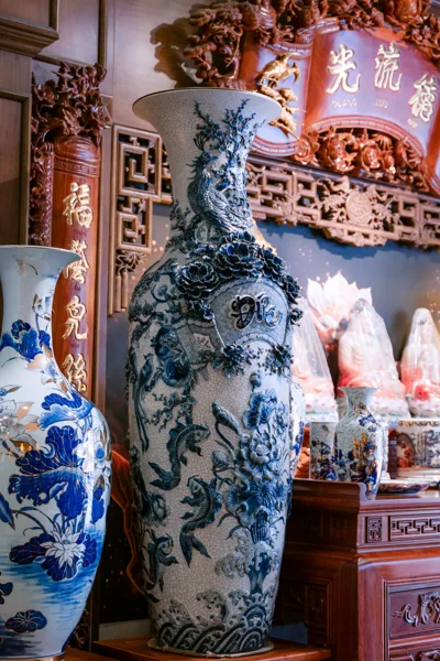 Bình cao nền sáng nhiều đường rạn nhỏ, hoa nổi xanh đậm quanh chữ Đức, chim đuôi dài ở cổ và cá sen trên thân; cạnh trái là bình vẽ hoa xanh trắng.