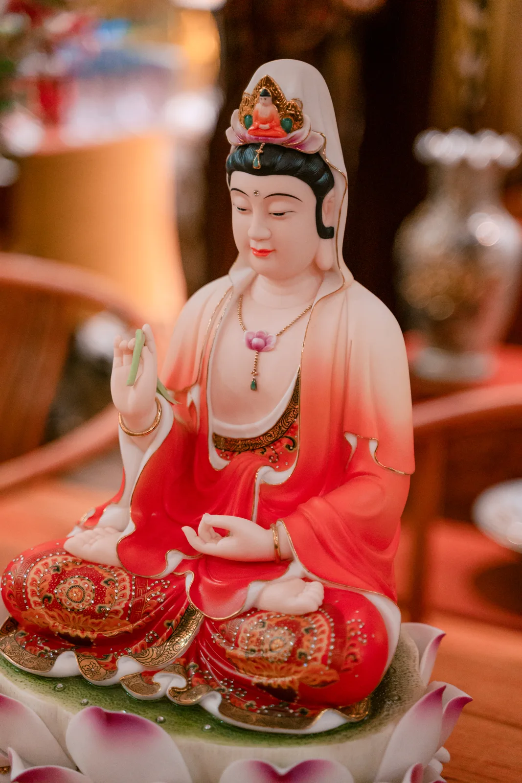 Tượng ngồi có khăn trắng, áo chuyển trắng sang đỏ, tay giơ giữ dải xanh, ngực có điểm hoa hồng và chân nhiều họa tiết trên bệ sen trắng hồng.