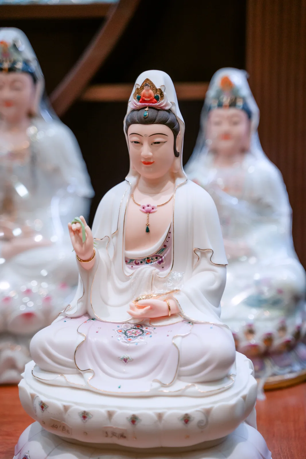 Tượng ngồi áo trắng điểm hoa hồng xanh, tóc đen phủ khăn trắng, tay nâng vật xanh và tay thấp đặt trước lòng trên đài sen trắng.