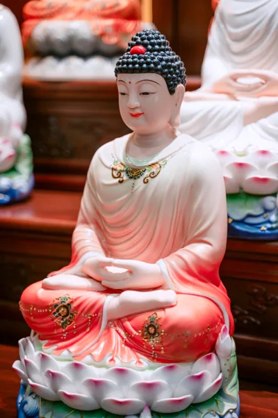 Tượng tóc xoắn đen có điểm đỏ trên đỉnh, áo trắng chuyển đỏ ở chân, hai tay đặt giữa lòng, ngồi trên đài sen trắng hồng và chân xanh.